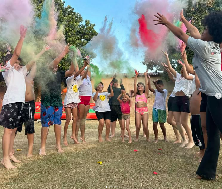 Festival de cores com crianças e adultos jogando pó colorido ao ar