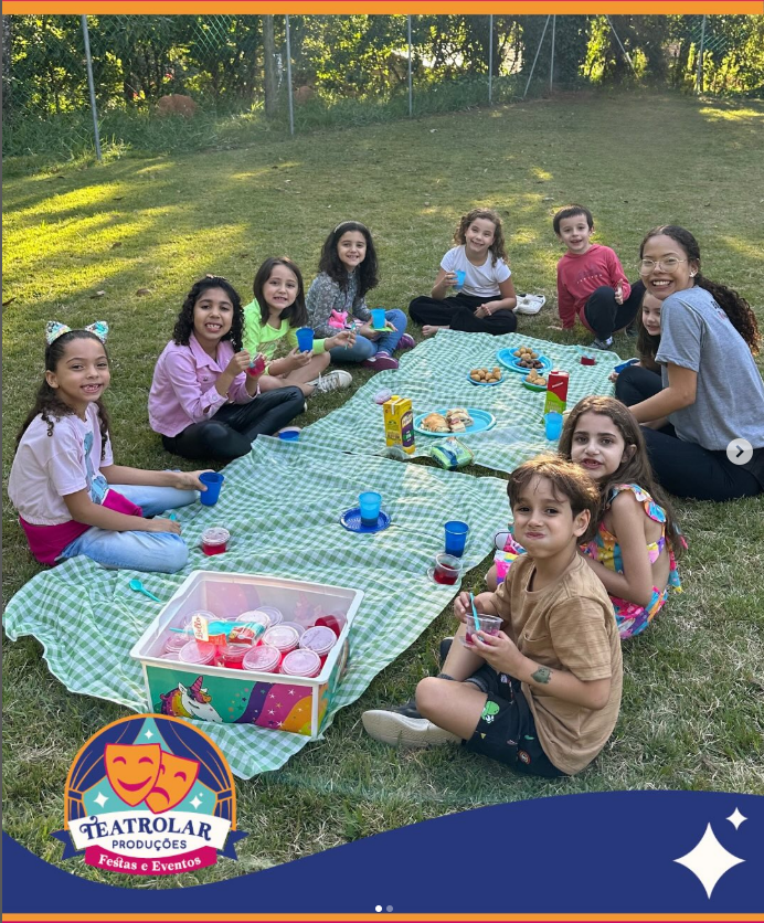 Piquenique divertido com crianças sentadas em toalha xadrez no gramado
